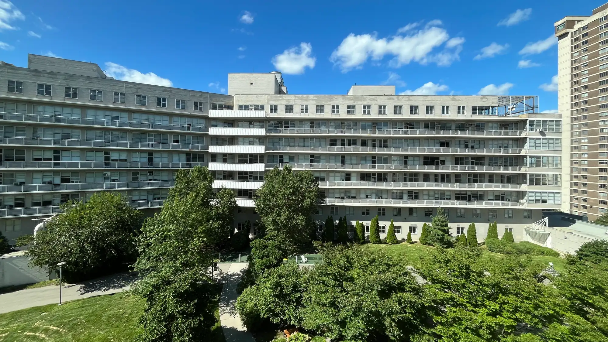 The Van Etten Building at the Albert Einstein College of Medicine, behind summer trees under a blue sky