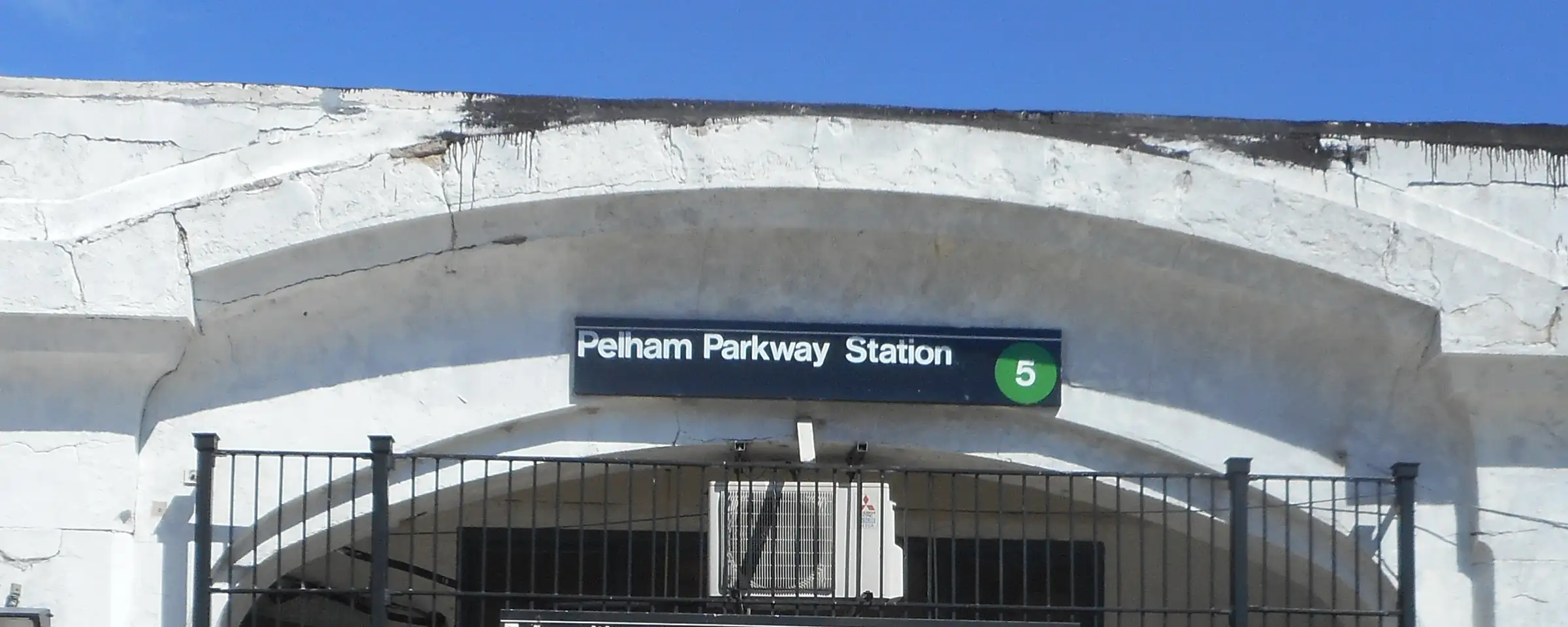 The arched entrance of the Pelham Parkway station on the Dyre Avenue line of the 5 train, under a blue sky