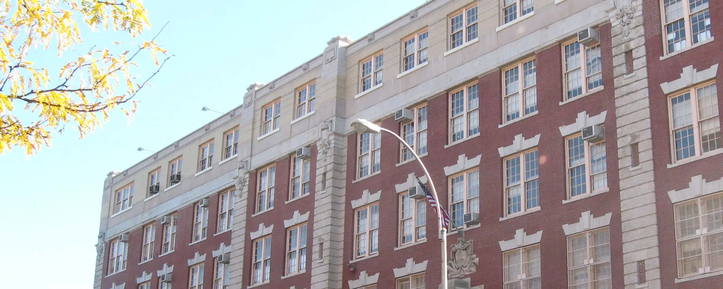 The brick and stone facade of P.S. 6 West Farms on East Tremont Avenue on a sunny day