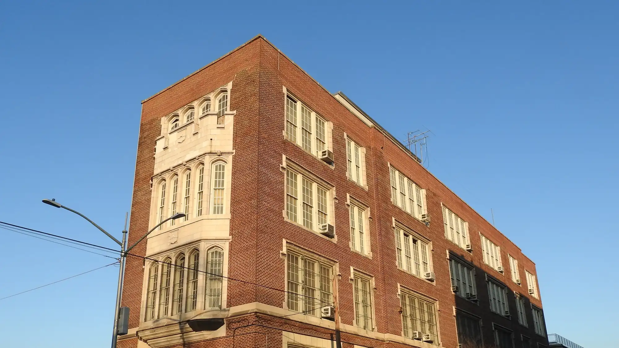 A brick schoolhouse at Frisby Avenue and Overing Street in Westchester Square under a clear blue sky